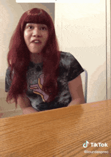 a woman with red hair is sitting at a table with a tiktok watermark on the bottom right