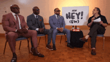 a group of men sitting in front of a sign that says hey