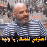 a bald man with a beard is wearing a striped shirt with arabic writing on it