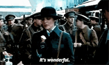 a woman in a hat is standing in front of a crowd of soldiers and says it 's wonderful