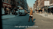 a man walking down a street with the words i 'm afraid of americans on the bottom
