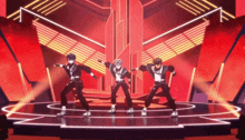 a group of people are dancing on a stage in front of a red background