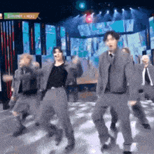 a group of men are dancing on a stage with a sign that says simmer next to them .