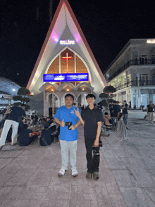 two young men standing in front of a church with a sign that says tri lieu on it