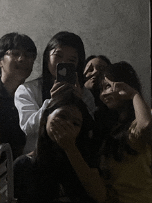 a group of people taking a selfie with a phone with a heart on it
