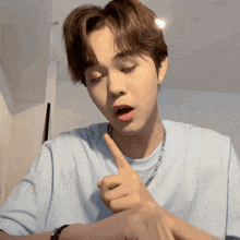 a young man wearing a blue t-shirt is pointing his finger at something