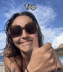 a woman wearing sunglasses giving a thumbs up with the word top above her head