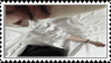 a woman in a white shirt is laying on a bed with her arms outstretched .