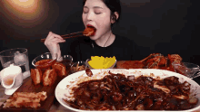 a woman with chopsticks is eating a large plate of food
