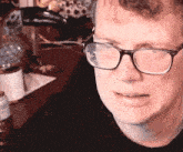 a close up of a man wearing glasses with a black shirt