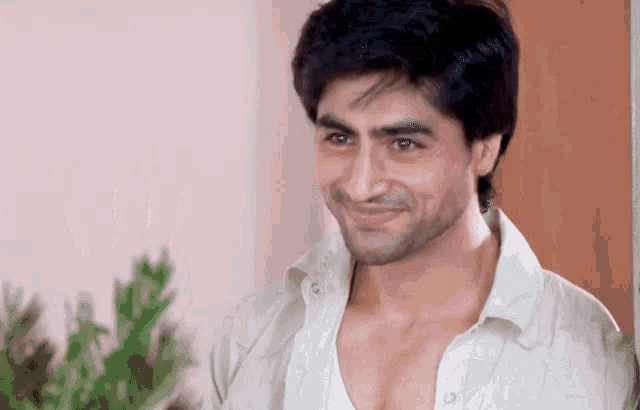 a man in a white shirt is smiling and looking to the side