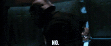 a man in a helmet is standing in front of a group of robots and saying no .