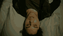 a man is laying upside down on a bed with his mouth open .