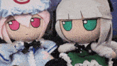 two stuffed dolls are sitting next to each other and one has a red eye and the other has green eyes