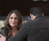 a woman in a black dress is crying while standing next to a man in a black jacket