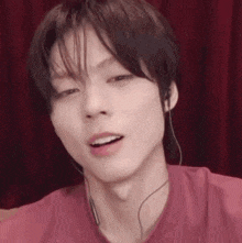a close up of a man wearing headphones and a pink shirt .