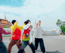 a group of people walking down a street with one wearing a white shirt with the word adidas on it