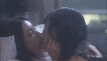 a couple of women kissing on a bed with their eyes closed