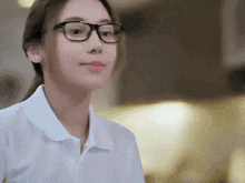 a woman wearing glasses and a white shirt looks to the side