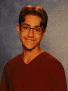 a young man wearing glasses and a red shirt