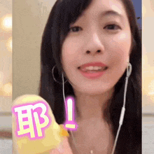a woman is wearing earphones and holding a yellow rubber duck with chinese writing on it