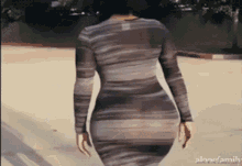 a woman in a striped dress is walking down a street with alonefamily written on the bottom of the screen