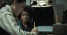 two women are sitting at a desk with a pencil in their hand