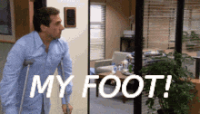 a man with crutches is standing in front of a door that says my foot !