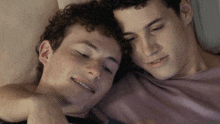 two young men are laying next to each other and one is smiling