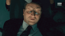 a man in a suit and tie is laying on the floor with a hbo max advertisement in the background
