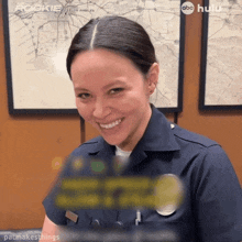 a woman in a police uniform is smiling in front of a map