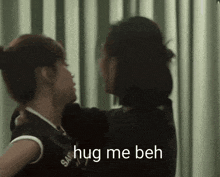 two women hugging with the words hug me beh on the bottom right