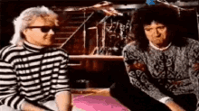 two men in striped sweaters are sitting next to each other .