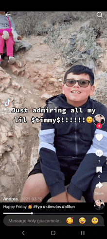a young boy wearing sunglasses and a black jacket is sitting on a rock