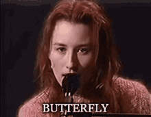 a woman is singing into a microphone and the word butterfly is on the bottom .