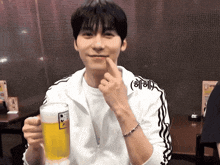 a man in a white adidas jacket holds a beer