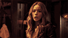 a woman with long blonde hair is standing in a dark room and looking at the camera