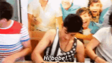 a group of people are sitting around a table and a man is sitting at a table and says hi babe .