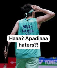 a man wearing a shirt that says sonny malaysia is holding a racket