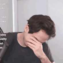 a man covering his face with his hand in front of a screen that says corey quality out