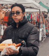a man wearing sunglasses is holding a hot dog in his hand