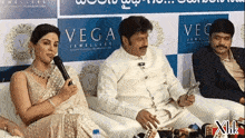 a group of people sitting in front of a sign that says vega jeweller 's