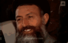 a man with a beard and a hat is smiling .