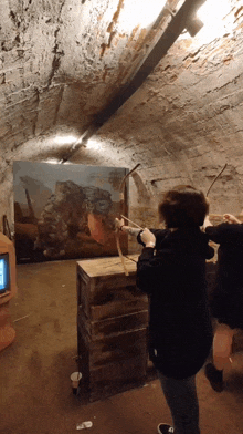a man holding a bow and arrow in front of a painting