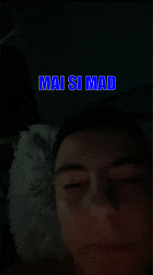 a man is laying in bed with the words mai si mad above his head