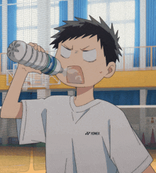 a boy wearing a white yonex shirt is drinking from a bottle