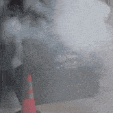 smoke is coming out of a trash can and a red and white traffic cone