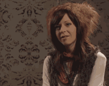 a woman wearing a furry hat and gloves is making a funny face