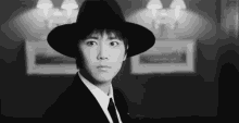 a black and white photo of a man wearing a hat and a suit