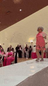 a woman in a pink dress walking down a runway